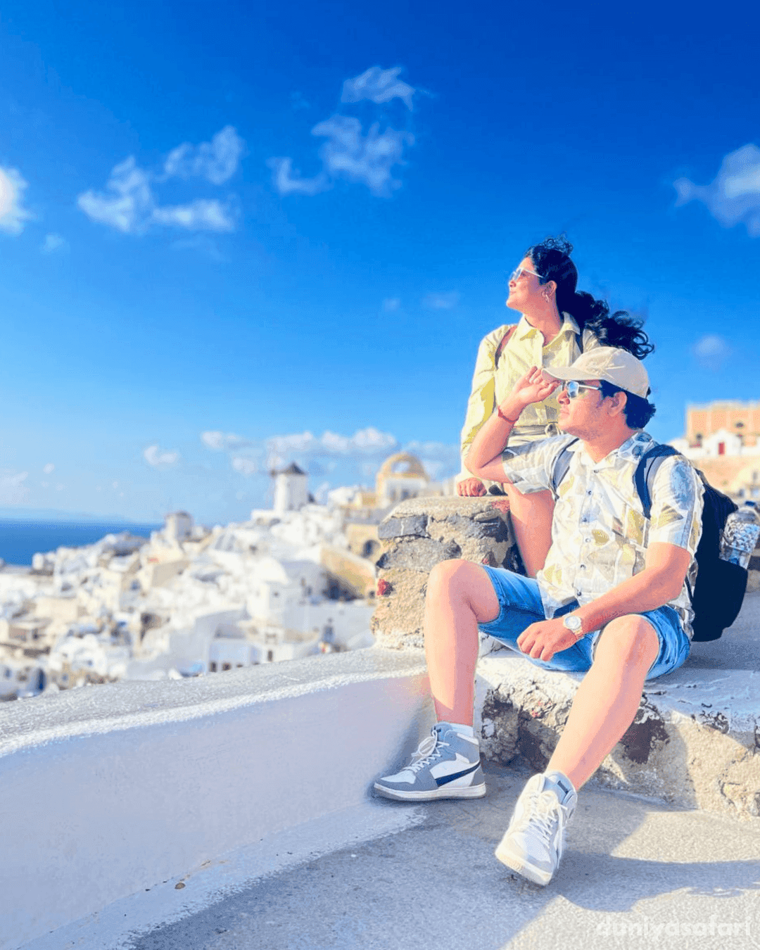 Couple overlooking the whitewashed buildings and Aegean Sea in Santorini, Greece